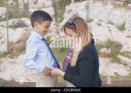 Lächelnde Mutter, die das Hemd ihres Sohnes zupft Stockfoto