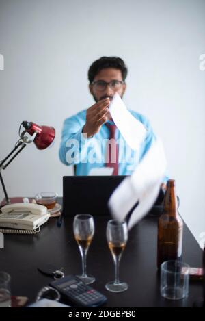 Indische Bengali groß, dunkel, hübsch Brünette junge Mann im Büro tragen genießen Erfolg, während auf einem Bürotisch in einem Büro / bpo sitzen Stockfoto