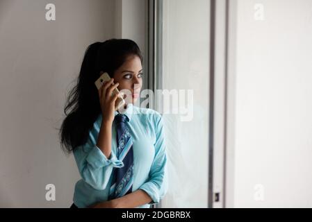 Indische Bengali attraktive Brünette junge Frau im Büro tragen vor einem Fenster in einem Firmenbüro / bpo / Call Center stehen. Stockfoto