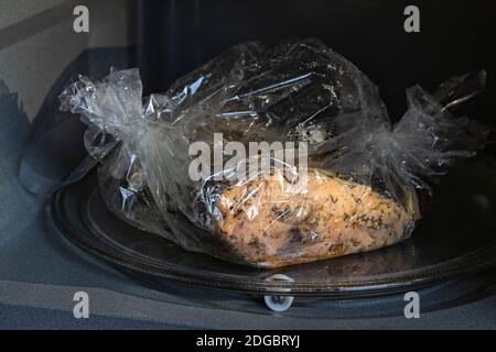 Gewürzter frischer Forellenfisch in einer Backform in einem Microvawe Ofen verpackt, gekocht, Nahaufnahme Stockfoto