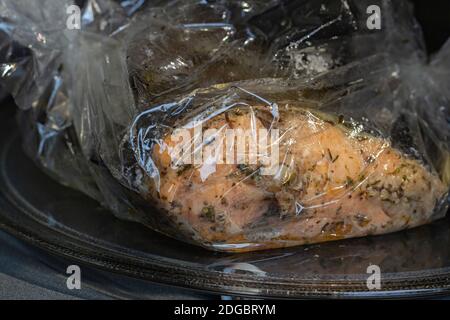 Gewürzter frischer Forellenfisch in einer Backform in einem Microvawe Ofen verpackt, gekocht, Nahaufnahme Stockfoto