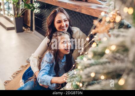 Mutter und Tochter bewundern Weihnachtsbaum zu Hause. Frohe Weihnachten und Frohes neues Jahr. Familie mit Spaß genießen Winterurlaub Feier Stockfoto