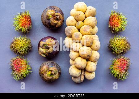 Verschiedene tropische Früchte von Rambutan, Mangostan und ein Zweig eines Langhahnes liegen auf einem leichten Holz-pu Stockfoto