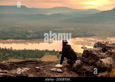 Frau auf einem Felsen sitzend, Blick auf Ubon Ratchathani, Isan, Thailand Stockfoto