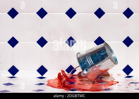 Ein Metalleimer fällt auf den Boden und spritzt die farbige Flüssigkeit aus. Stockfoto