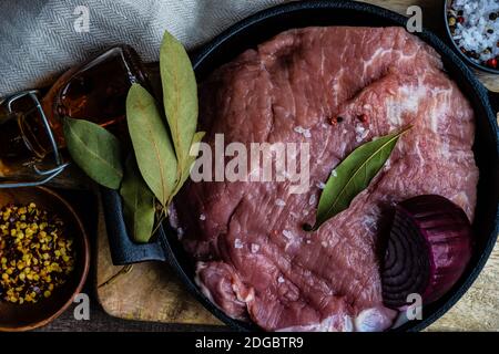 Schweinefleisch in einem Topf mit roten Zwiebeln, Lorbeerblättern, Chili und Salz Stockfoto