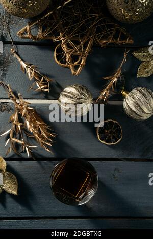 Glas Whisky mit Zimtstange und goldener Weihnachten Dekorationen Stockfoto