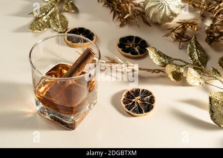 Glas Whisky mit Zimtstange und goldener Weihnachten Dekorationen Stockfoto