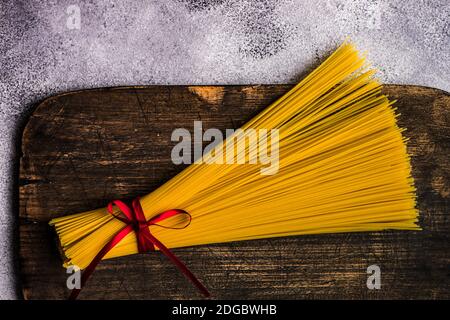Bündel von rohen Spaghetti mit einem Band auf einem gebunden Schneidebrett Stockfoto