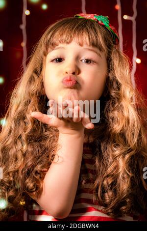 Porträt eines lächelnden Mädchen weht Küsse vor Weihnachtsbeleuchtung Stockfoto
