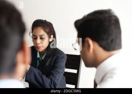 Junge und energische Untergebene diskutieren im indischen Büro mit weiblicher Chefin. Indisches Unternehmen Stockfoto