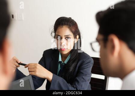 Junge und energische Untergebene diskutieren im indischen Büro mit weiblicher Chefin. Indisches Unternehmen Stockfoto