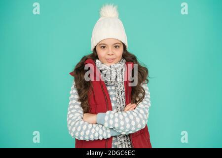 Happy Holiday. Kalte Jahreszeit Stil weihnachtsaktivität. Kindheitsglück. Thermische Kleidung. Happy teen Mädchen tragen warme Kleidung. Winter Kid Mode. Kind mit langen lockigen Haaren in gestrickten Hut. Stockfoto