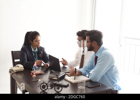 Junge und energische Untergebene diskutieren im indischen Büro mit weiblicher Chefin. Indisches Unternehmen Stockfoto