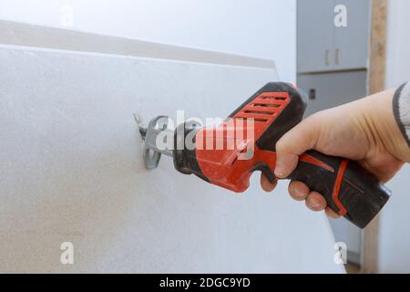 Arbeiter schneidet mit einer schmutzigen Säge Trockenbau schneiden Gipskarton Stockfoto