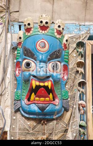 Geschnitzte, grausige Wandmaske im tibetischen Stil. Souvenir zum Verkauf für Touristen. Leh, Ladakh, Jammu und Kaschmir, Indien Stockfoto