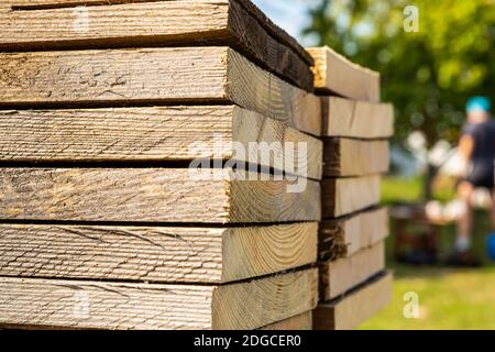 Hoher Stapel von alten und beigen Planken, Seitenansicht auf einem verschwommenen Hintergrund der Konstruktion Stockfoto