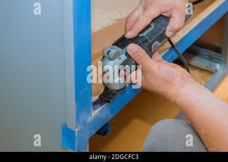 Auftragnehmer mit oszillierenden multifunktionalen Schneidwerkzeug für Handyman schneiden Loch in Küchenmöbel Stockfoto