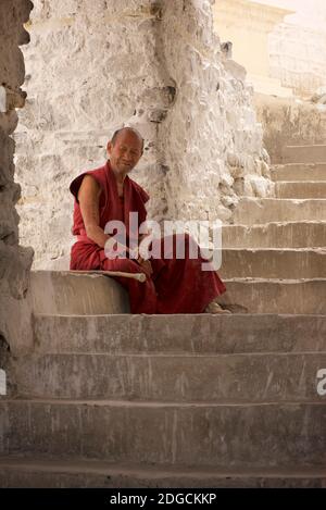 Portrait eines Mönchs auf einer Treppe im Kloster Diskit, auch bekannt als Deskit Gompa oder Diskit Gompa. Das Kloster ist das älteste und größte buddhistische Kloster im Nubra-Tal. Es gehört zur Gelugpa-Sekte des tibetischen Buddhismus. Ladakh, Jammu und Kaschmir, Indien Stockfoto