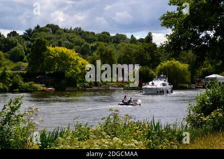 Familie auf einem kleinen Motorboot, Kreuzfahrt entlang der Themse, wie eine Luxusyacht nähert. Bourne End, Buckinghamshire, Großbritannien. Stockfoto