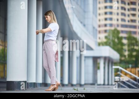 Mädchen in vollem Wachstum betrachtet die Armbanduhr in der Nähe der Business Gebäude Stockfoto