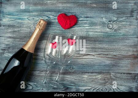 Champagner, zwei Gläser und rote Herzen auf Holzgrund. Stockfoto