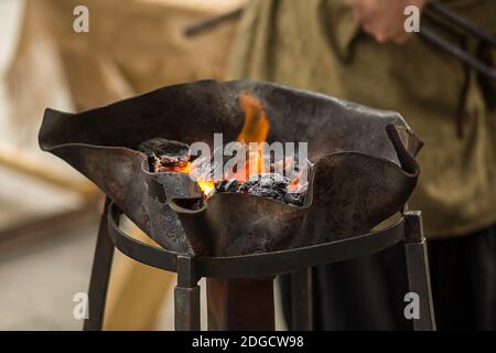 Orangefarbene Feuerkohlen für Schmiedehorn in einem durchbrochenen Metall Schüssel mit Blasen Stockfoto