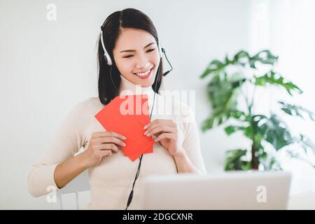 Glücklich asiatische junge Frau machen Abstand Video Anruf und zeigen Roter Umschlag zur Feier des chinesischen Neujahrjahres Stockfoto