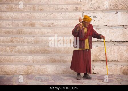 Portrait eines freundlichen, älteren Mönchs mit Sonnenbrille und Gebetrad im Hemis Kloster, Hemis, Ladakh, Jammu und Kashmir, Indien Stockfoto