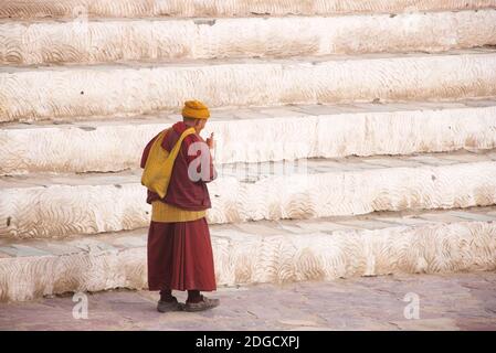 Portrait eines freundlichen, älteren Mönchs mit Sonnenbrille und Gebetrad im Hemis Kloster, Hemis, Ladakh, Jammu und Kashmir, Indien Stockfoto