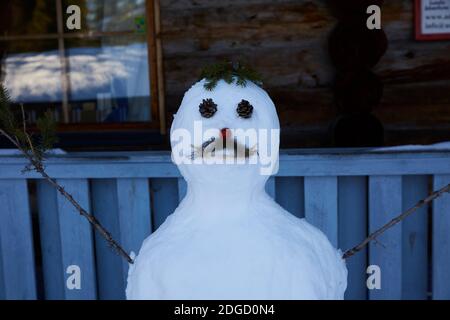 Schneemann mit Schnurrbart vor der Blockhütte in Lappland, Polarkreis, Finnland Stockfoto