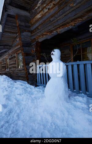 Schneemann mit Schnurrbart vor der Blockhütte in Lappland, Polarkreis, Finnland Stockfoto