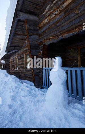 Schneemann mit Schnurrbart vor der Blockhütte in Lappland, Polarkreis, Finnland Stockfoto