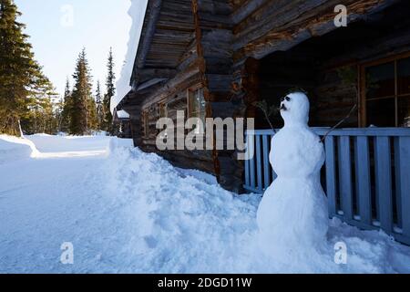 Schneemann mit Schnurrbart vor der Blockhütte in Lappland, Polarkreis, Finnland Stockfoto