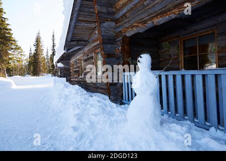 Schneemann mit Schnurrbart vor der Blockhütte in Lappland, Polarkreis, Finnland Stockfoto