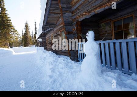 Schneemann mit Schnurrbart vor der Blockhütte in Lappland, Polarkreis, Finnland Stockfoto