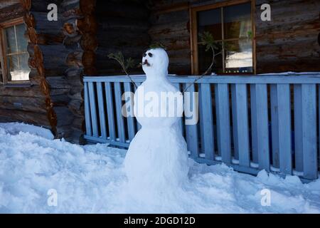 Schneemann mit Schnurrbart vor der Blockhütte in Lappland, Polarkreis, Finnland Stockfoto