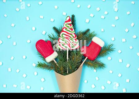 Geschenk grünen Tannenbaum in Handwerk Papiertüte mit Weihnachten Süßigkeiten und Mini Marshmallows auf blauem Hintergrund. Null-Abfall-Urlaubskonzept. Idee für Urlaub Stockfoto