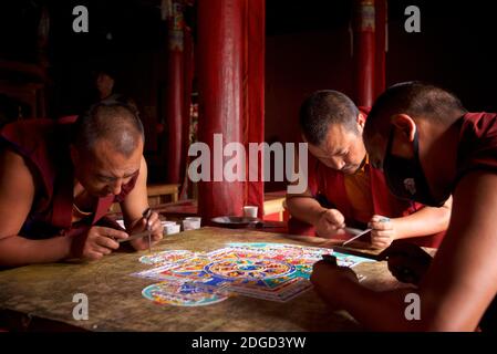 Mönche im Lamayuru Kloster, Ladakh Schaffung eines Mandala von farbigem Sand. Lamayouro, Ladakh, Jammu und Kaschmir, Indien. Ein Sandmandala wird ritualistisch abgebaut, sobald es abgeschlossen ist und seine begleitenden Zeremonien und das Betrachten beendet sind, um den buddhistischen doktrinären Glauben an die vorübergehende Natur des materiellen Lebens zu symbolisieren. Stockfoto