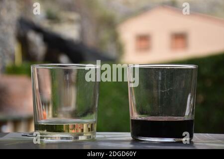 Gläser Weiß- und Rotwein im Picknickbereich mit Gebäude im Hintergrund. Stockfoto