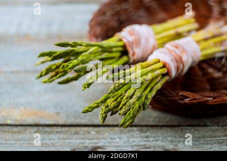 Spargel mit gebratenem Speck, auf einem hölzernen Hintergrund, rustikaler Stil Stockfoto