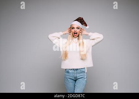 Schöne blonde Frau in Santa Hut schreien im Studio Stockfoto