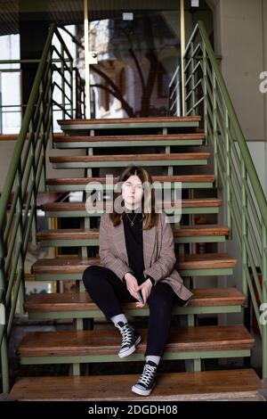 Das Mädchen sitzt auf den Stufen der Stadt Haus Stockfoto