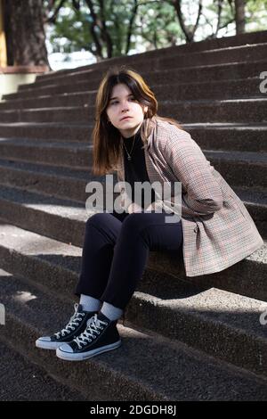 Mädchen sitzt auf den Steinstufen eines Quadrats in Buenos Aires Stockfoto