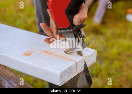 Ein Mann schneidet ein Brett aus Holz mit einem Puzzleteil eines Schneidens Holzbrett mit Sägestaub. Stockfoto