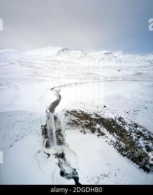 Drone Blick auf Wasserfall im Hochland gelegen und mit bedeckt Schnee in Island Stockfoto