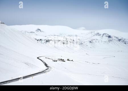 Leere kurvenreiche Straße zwischen schneebedecktem Hochland in der Wüste am Wintertag In Island Stockfoto