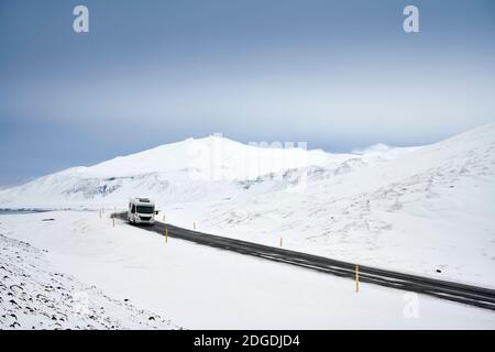 Einsame LKW fahren entlang der Straße zwischen wilden schneebedeckten Gelände in Winter Island Stockfoto