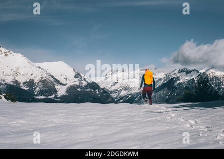 Junger Mann, der im Tiefschnee gegen den schneebedeckten Berg in den Pyrenäen, Huesca, Spanien, läuft Stockfoto