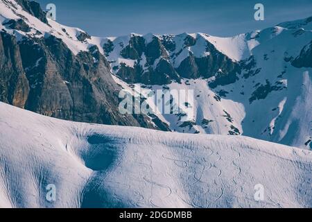 Zwei nicht erkennbare Backcountry Skifahrer in Richtung Bergrücken gegen bewölkten Himmel und schneebedeckten Bergen, Französisch Pyrenäen. Stockfoto